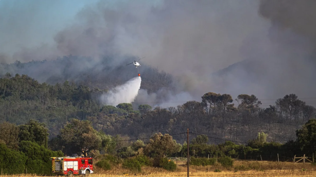 A firefighting helicopter battles the blaze in the Les Gavarres mountain range in Catalonia, with fire crews securing the ground below./ Photo: Social media