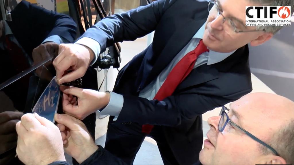 An ISO decal is being attached to a bus on the Busworld fair in Belgium. Screenshot from the CTIF / UITP video.